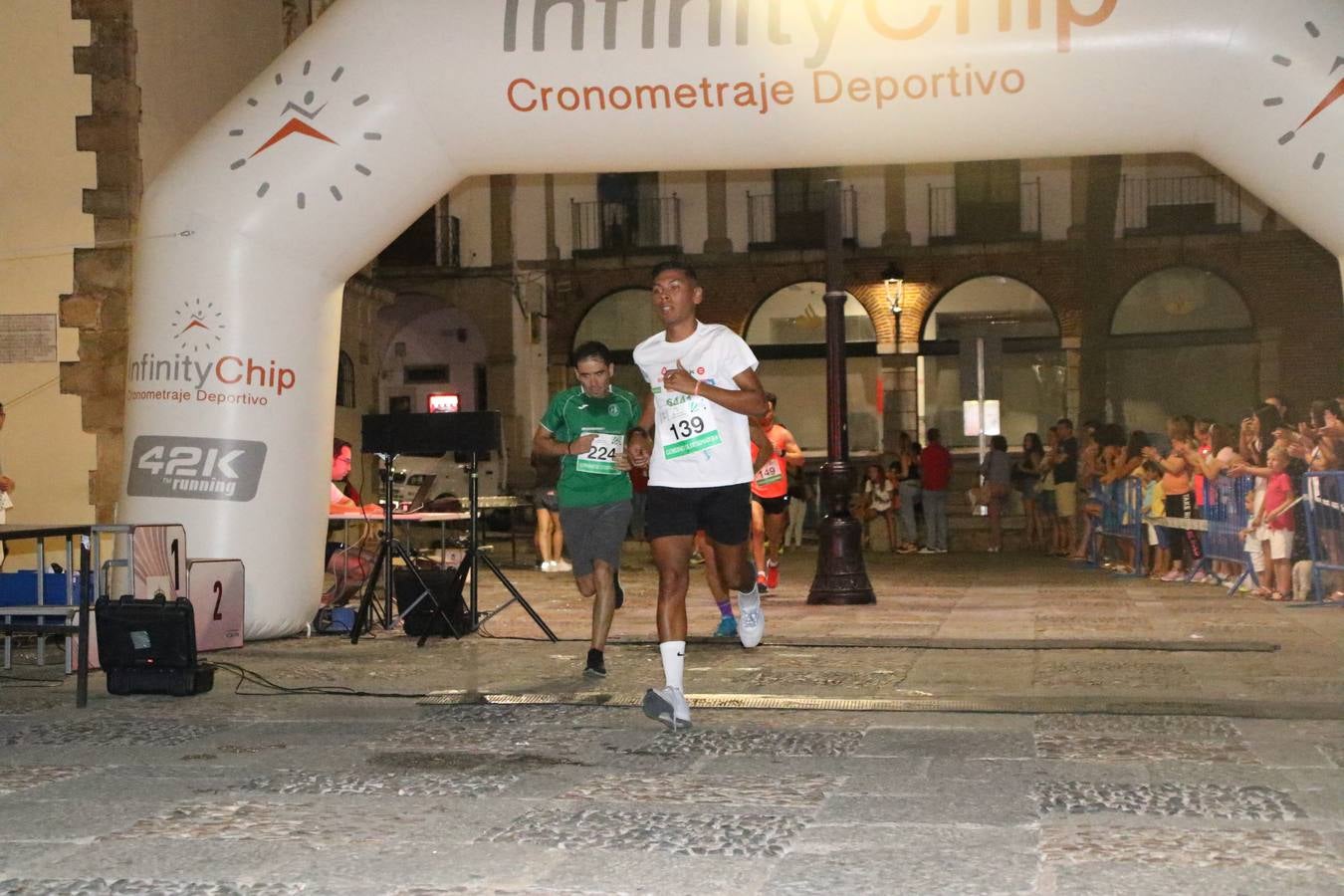 La Plaza de España de Jerez de los Caballeros acogió, ayer, la V Carrera Popular Nocturna 'Recorriendo el Medievo', organizada por el Ayuntamiento del municipio con la colaboración del Plan de Dinamización Deportiva de la Mancomunidad Sierra Suroeste. Las principales calles del municipio volvieron a convertirse en el mejor escenario para el desarrollo de esta prueba deportiva que, año tras año, se consolida como una de las citas más destacadas del calendario estival jerezano y en la que la solidaridad, también, está muy presente. Así, se lograron recaudar 153 kilos y 22 euros que irán destinados al almacén de alimentos que gestiona la Asamblea local de Cruz Roja en el municipio.En esta edición, han participado unos 200 corredores de la localidad y alrededores, siendo Manuel Gómez Lucas y Tina María Ramos, vencedores de la clasificación general.