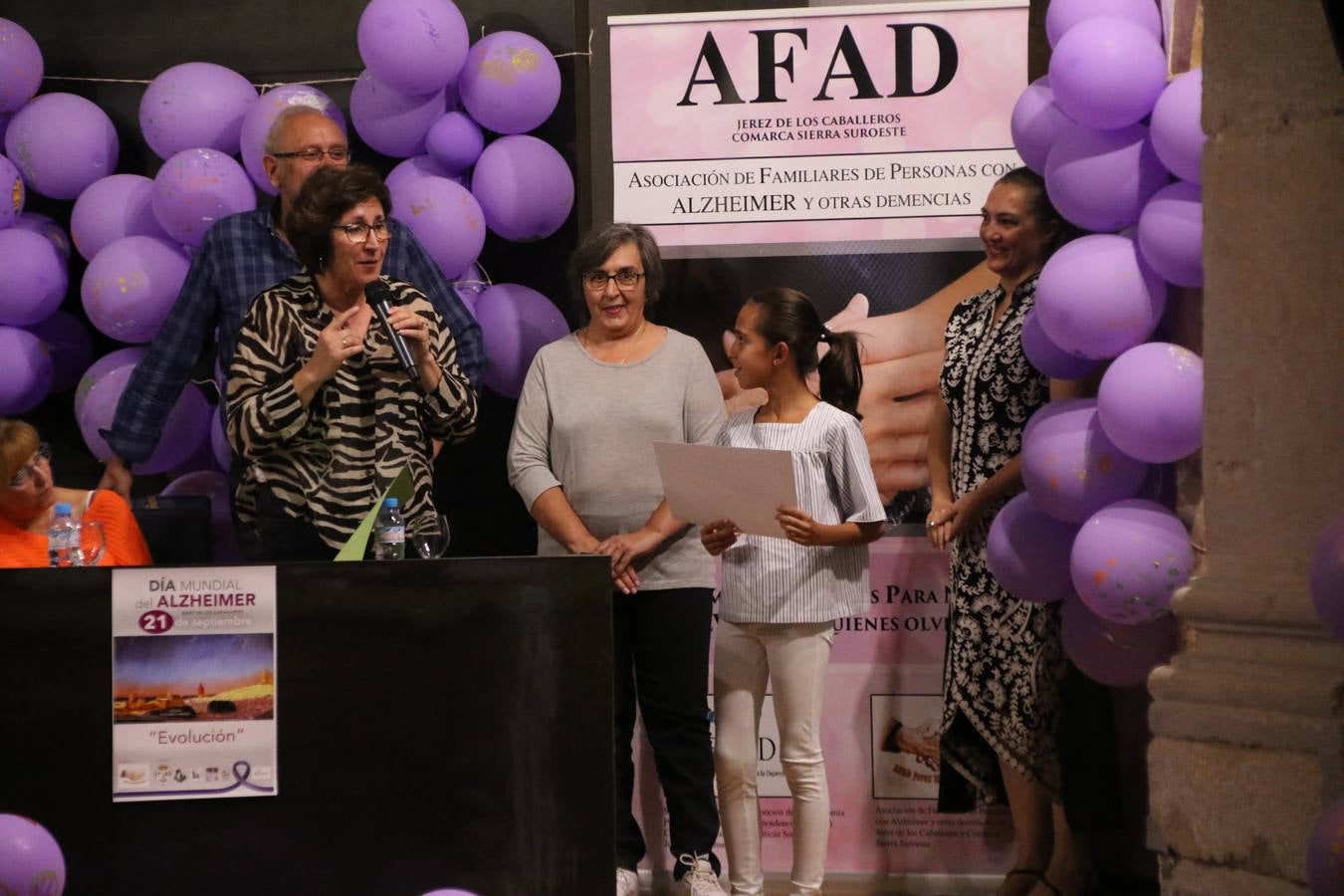 Ante las condiciones climatológicas adversas, el auditorio del Conventual San Agustín se convirtió en el mejor escenario para acoger las actividades que, con motivo del Día Mundial del Alzhéimer, la Asociación de Familiares de Personas con Alzheimer y otras Demencias de Jerez de los Caballeros y Comarca Sierra Suroeste (AFAD) había preparado en el municipio. Una gran pancarta con el lema 'Evolución', realizada por los alumnos del Colegio de Educación Especial 'Nuestra Señora de Aguasantas', presidió el escenario, y una marea de globos morados con distintos dibujos, realizados por los alumnos de los colegios 'Sotomayor y Terrazas' y 'El Rodeo', tiñó de color, empatía, sensibilidad y creatividad el citado auditorio.La jornada comenzó con la canción 'Estoy contigo' de la Oreja de Van Gogh. A continuación, tuvo lugar una mesa redonda en la que cinco personas contaron su testimonio en relación a esta enfermedad. Posteriormente, se dio paso a la lectura de un manifiesto; la entrega de diploma a las personas y colectivos colaboradores, y la lectura de dos cuentos infantiles.