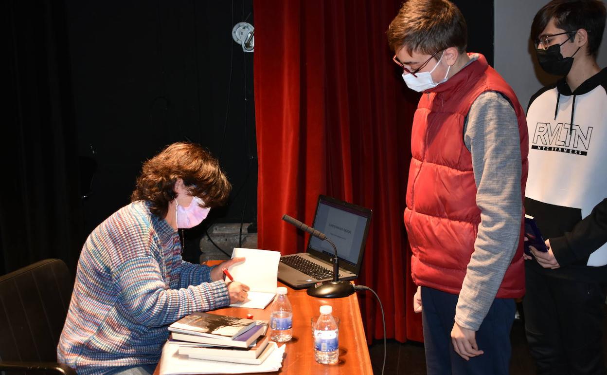 Pilar Galán firma libros a varios alumnos asistentes al encuentro.
