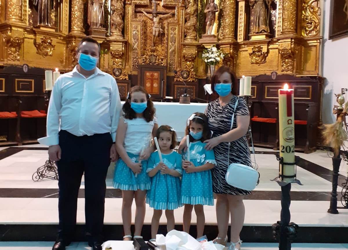 Las tres niñas portan las velas del bautismo junto a sus padres. La más alta celebrará la primkera comunión en septiembre 
