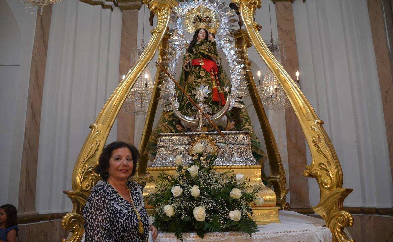 La Hermana Mayor Mari Carmen Tinoco, junto a la Imagen y trono de la Virgen 