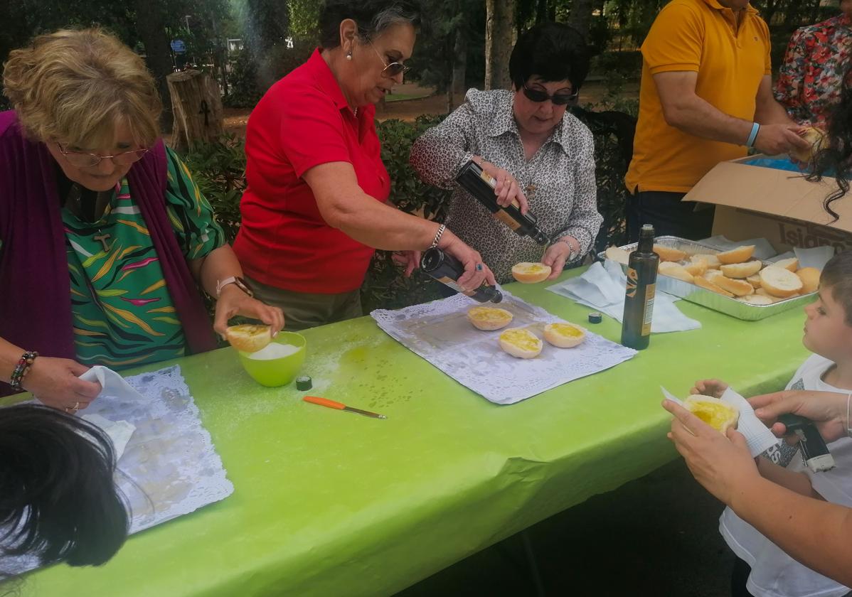 LAs personas colaboradoras reparten el pan con aceite y azúcar