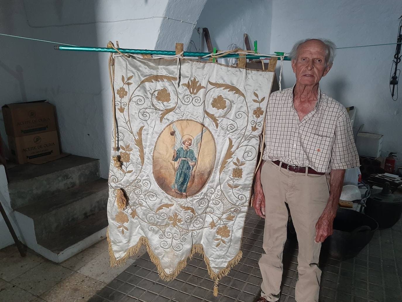Rafael Santiago junto al estandarte de San rafael que aún conserva en su casa.