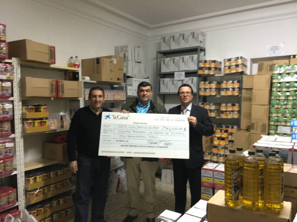Uno de los responsables de la oficina santeña hace entrega del cheque en Cáritas