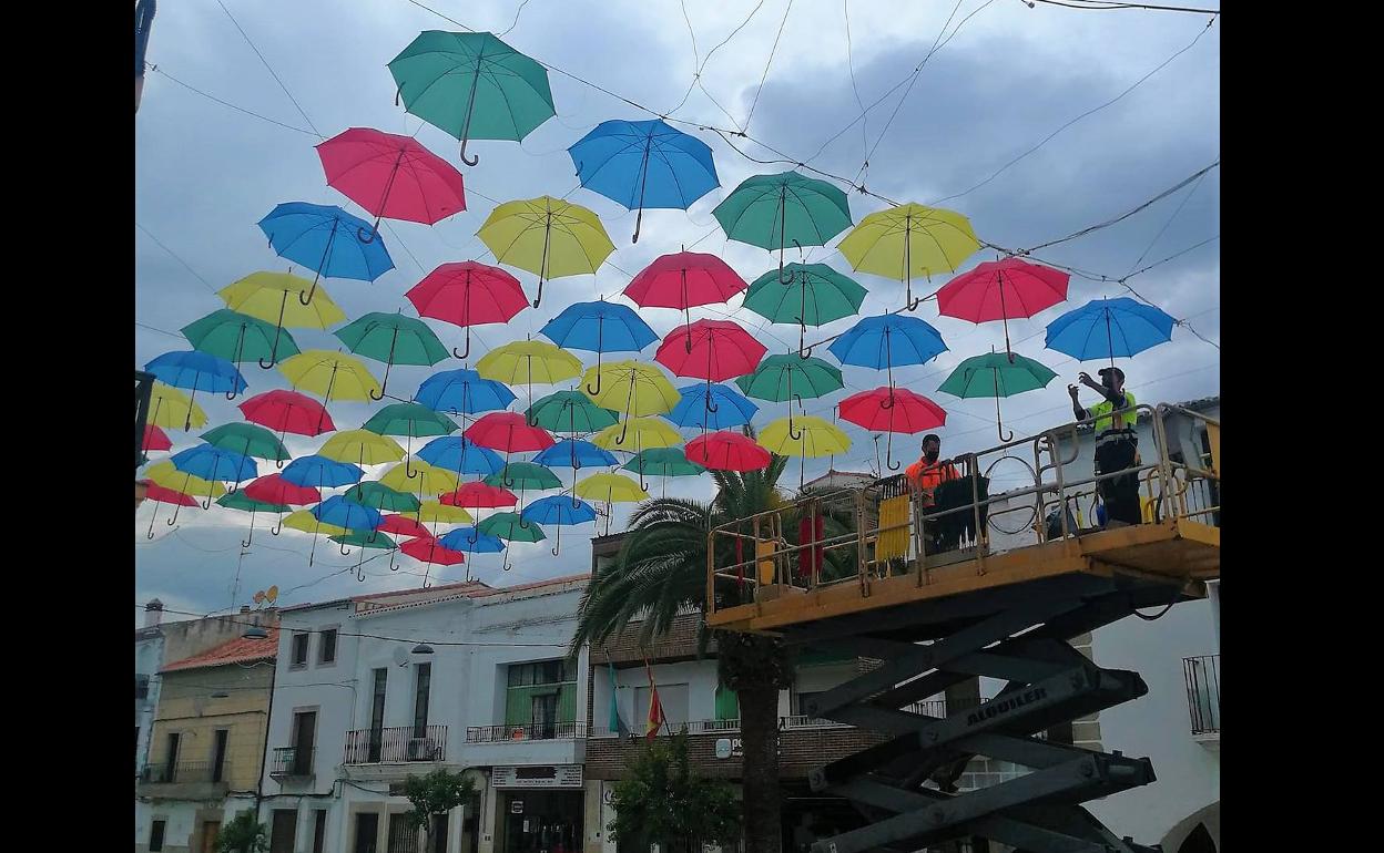 Trabajadores municipales comenzando a colocar los paraguas de colores. 