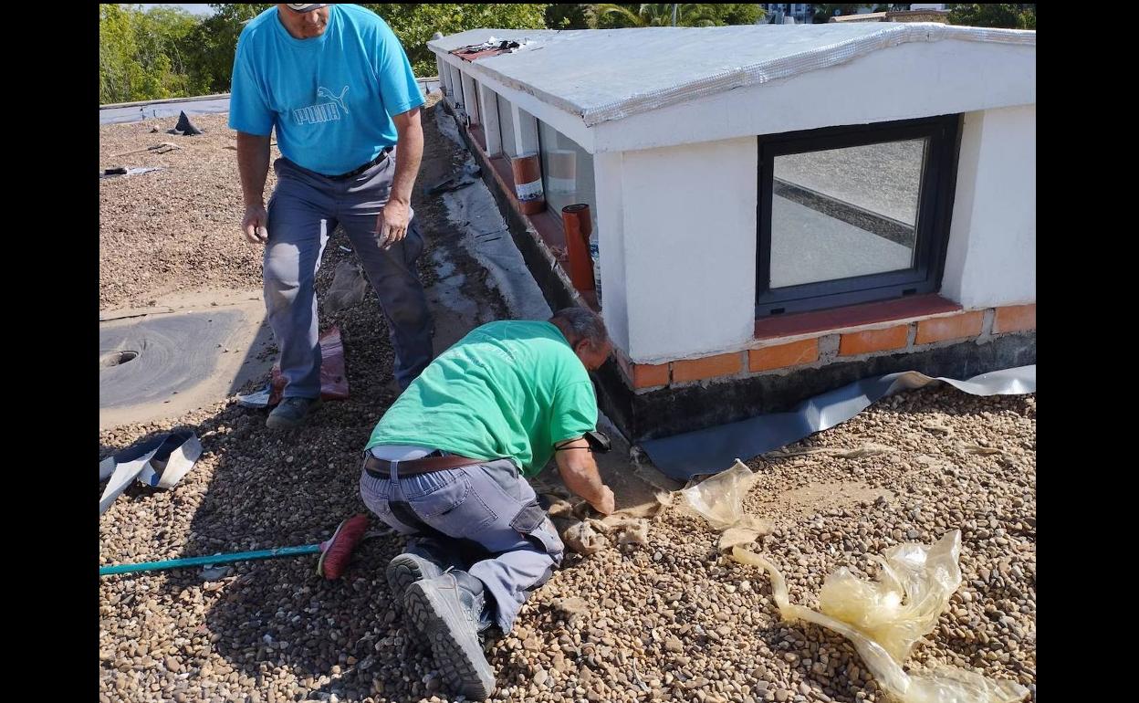 Dos trabajadores en el tejado del Centro de Día comenzando con las obras. 