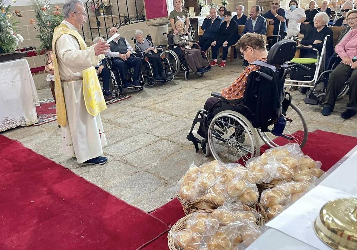 El párroco ofiando la misa junto a los bollos que fueron bendecidos al final de la misma.