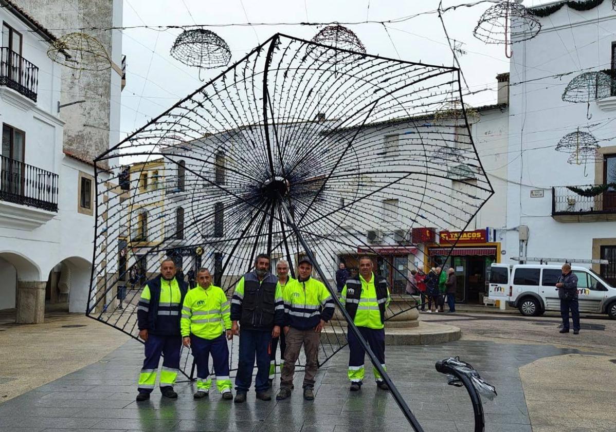 Imagen principal - Trabajadores municipales instalando el paraguas gigante. 