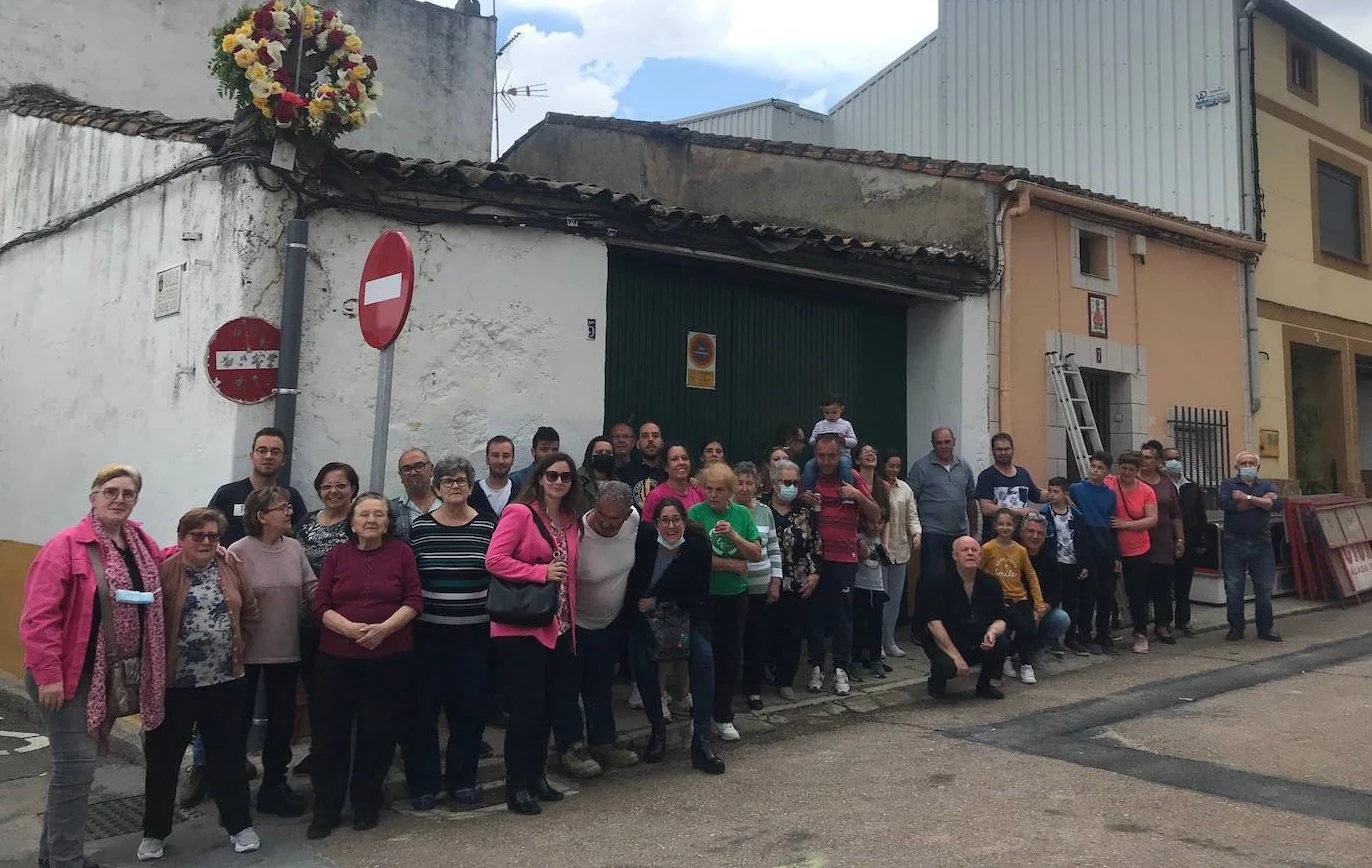 Los vecinos de la calle Cuesta posan bajo la cruz de piedra engalanada con la corona de flores 