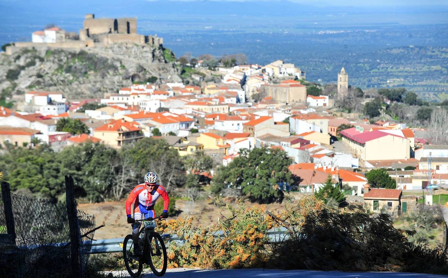 Uno de los ciclistas con el castillo de Montánchez de fondo. 