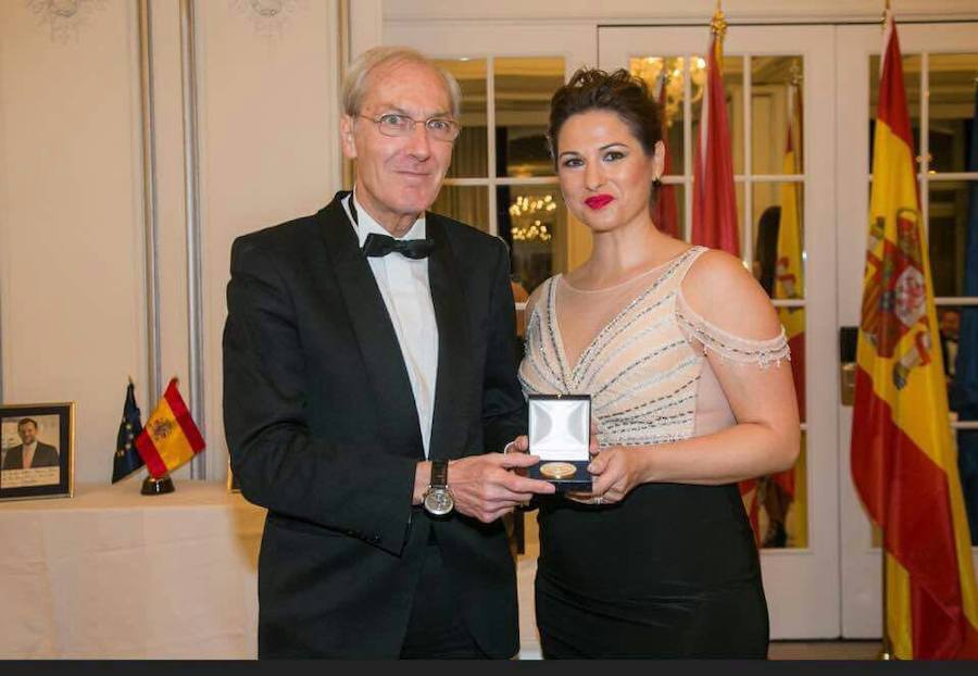 Lorena Cuadrado recibiendo la medalla de manos del fundador del foro. 