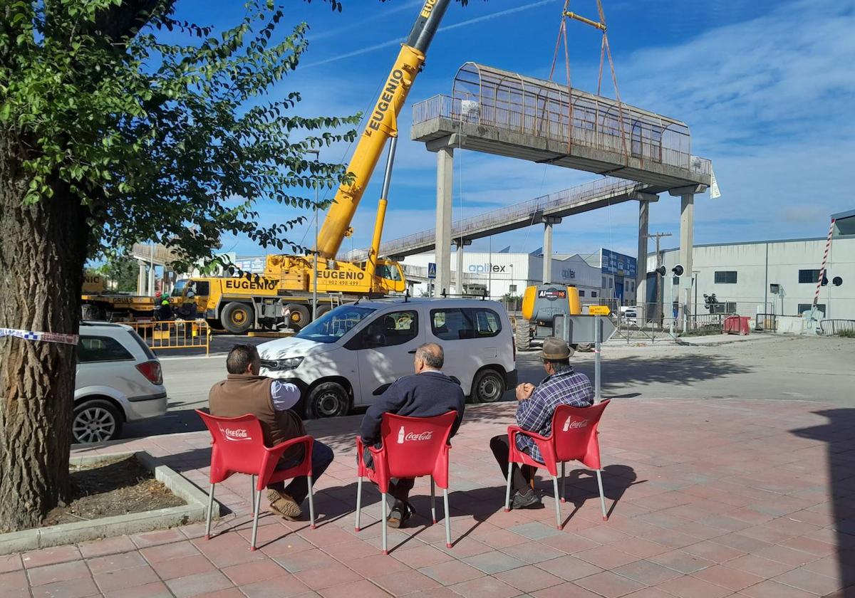 Sentados, plácidamente, para observar el desmantelamiento de la pasarela peatonal