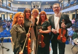 Los músicos moralos con la directora de la orquesta, en el centro