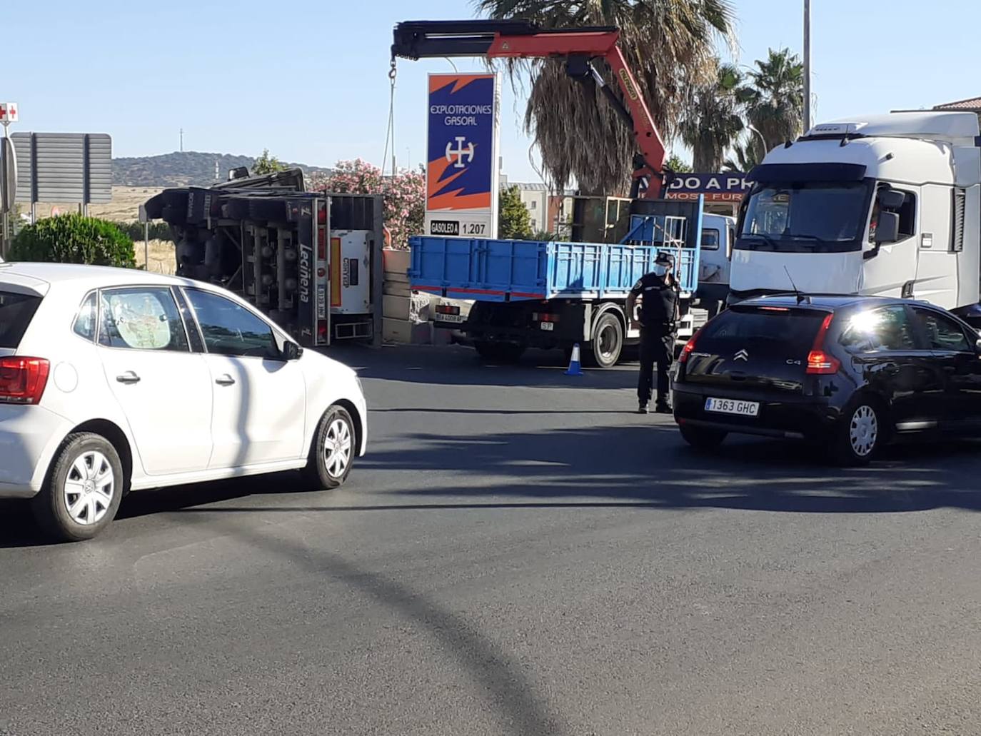Imagen principal - Arriba, un agente de la Policía Local de Olivenza, regula el tráfico en la intersección. Abajo, camión volcado y vigas de hormigón que transportaba. 