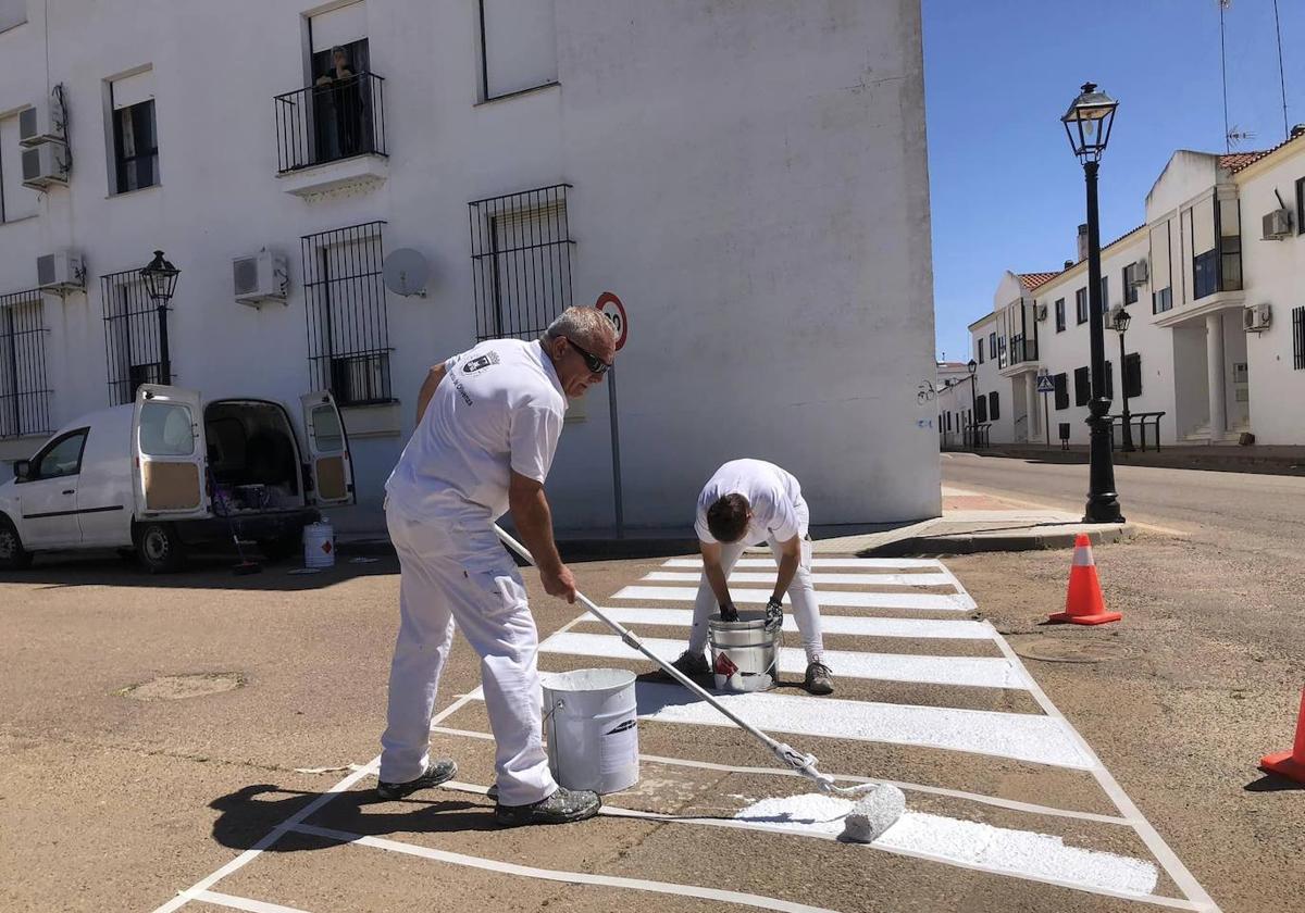 Los operarios se afanan en las labores de pintura.