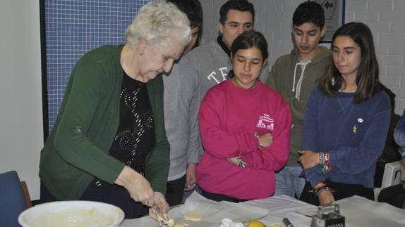 Carmen Costa, usuaria de la residencia CASER, enseña a hacer bolluelas de Cuaresma a los escolares. 