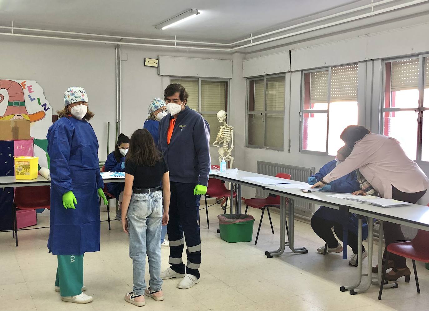 El pediatra y una enfermera hablan con una alumna antes de recibir la vacuna. 