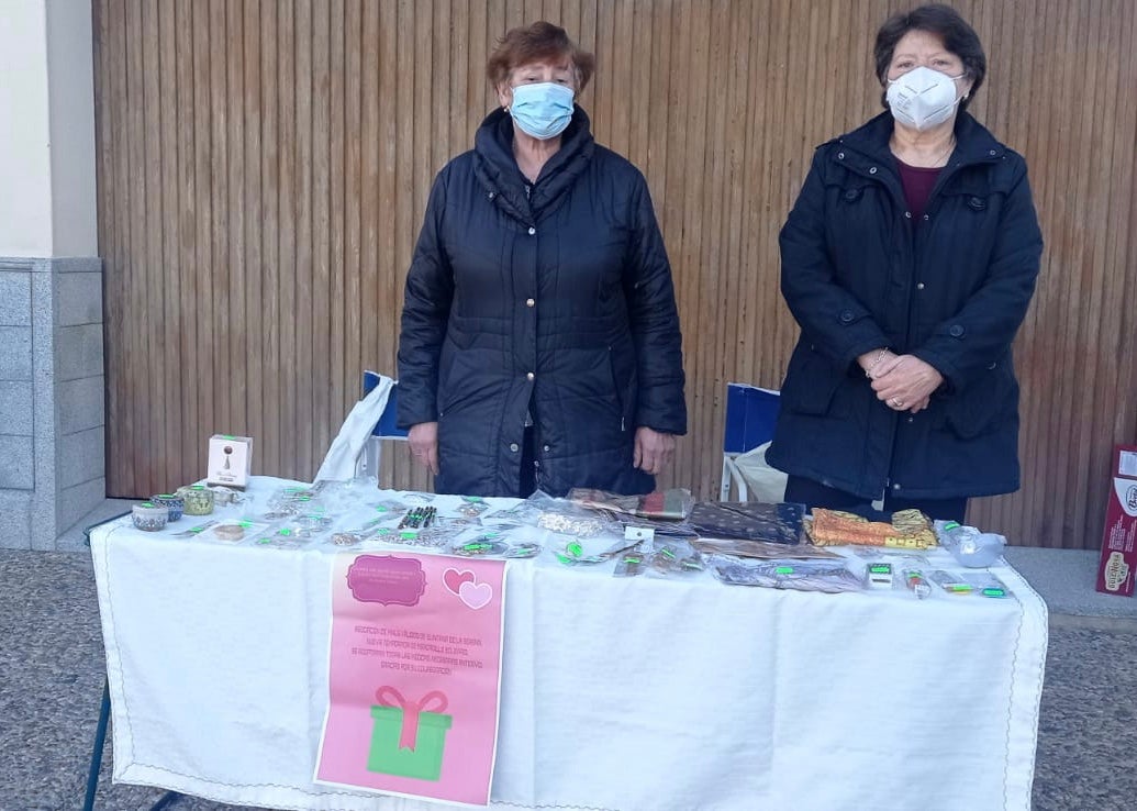 Dos miembros de la asociación atienden en el puesto solidario 