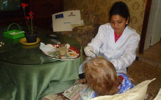 Una mujer asiste a una anciana dependiente.
