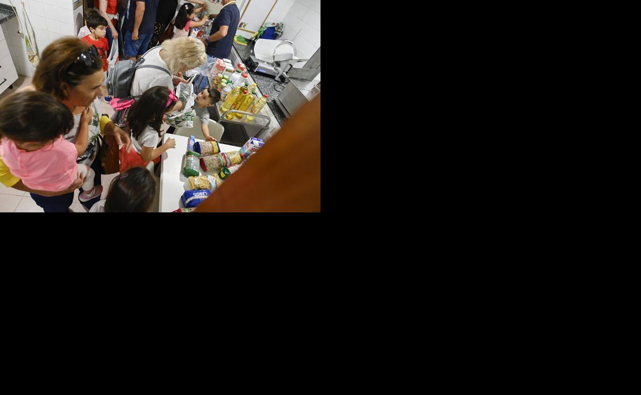 Los escolares junto con sus abuelos dejando la comida en la cocina del comedor social de Badajoz.