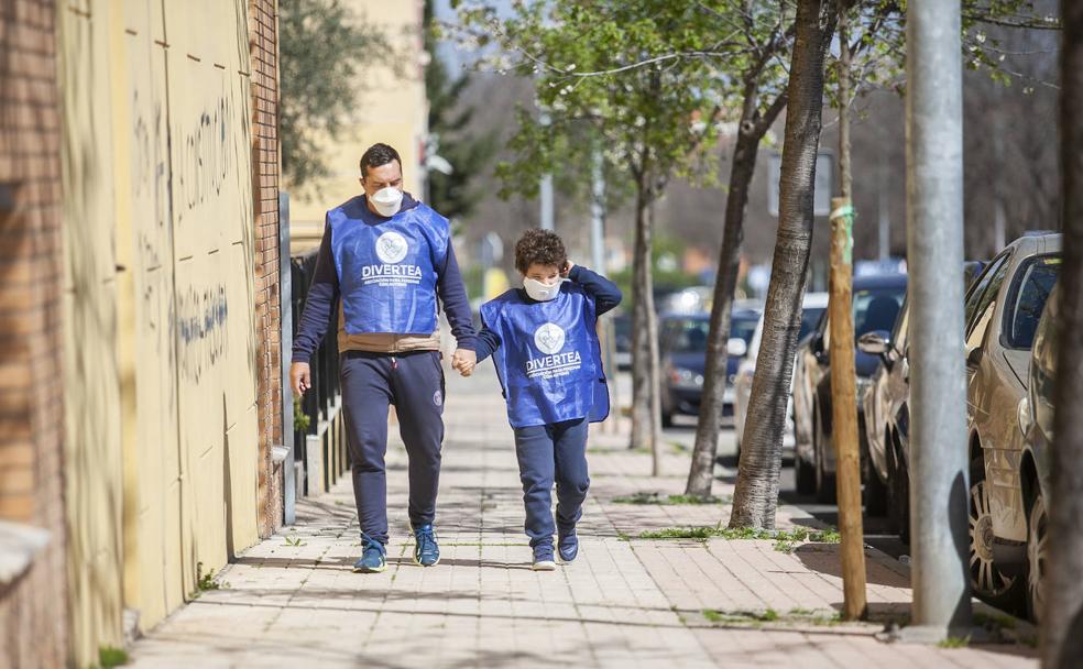 Hugo y su padre, ambos con un chaleco azul de Divertea, paseando por el barrio cacereño de Montesol. 