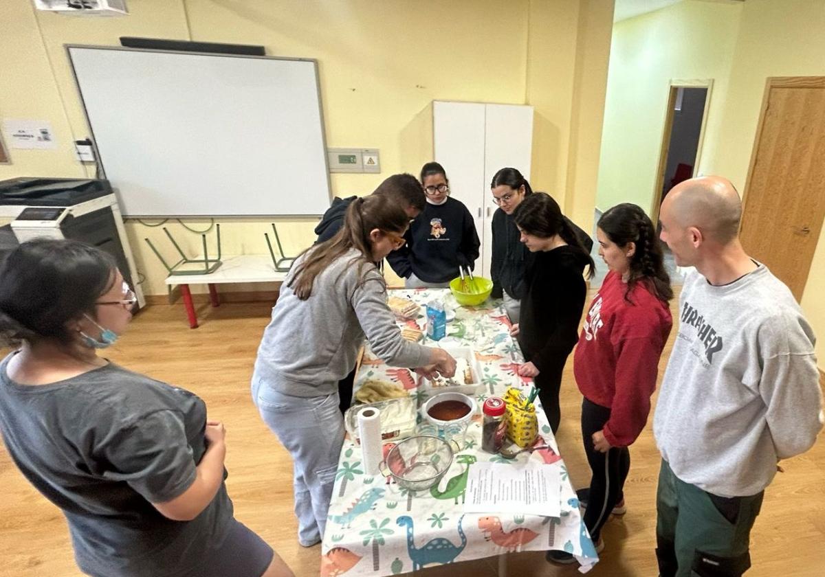 Un grupo de jóvenes prepara una de las recetas seleccionadas en el taller de cocina y compra.