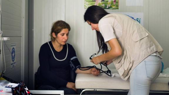 Miembro de Médicos del Mundo atiende a una mujer en un campamento de refugiados.