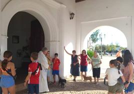 El párroco de la localidad dando la bendición a varias de las mascotas asistentes.