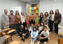 Integrantes de la comunidad educativa, tras la presentación del prooyecto, junto al contenedor de ropa.