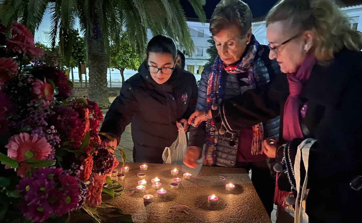 Tres mujeres encienden velas en el monumento homenaje a las víctimas de la violencia de género. 