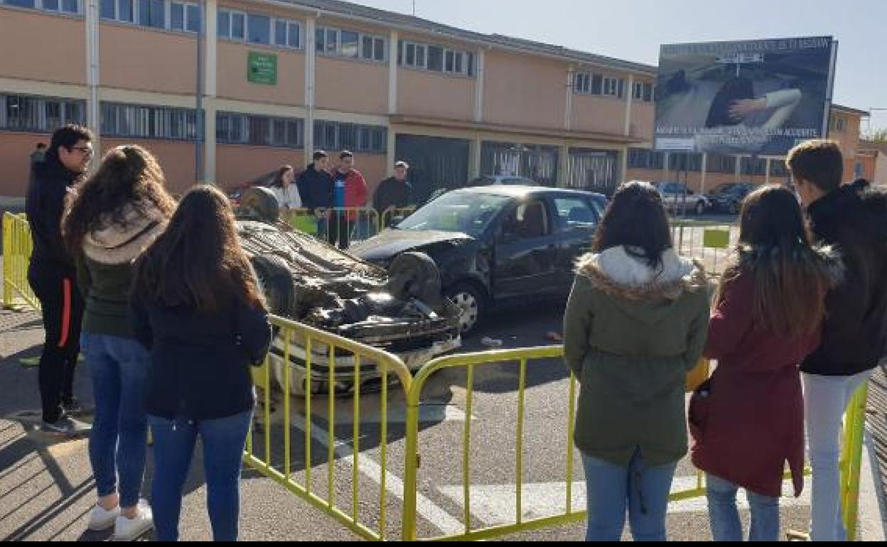 Jóvenes comtemplan una exposición de coches accidentados. 