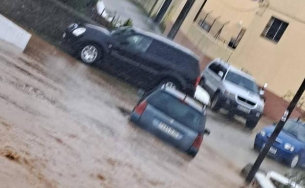 Vehículo rescatado con su conductor del embalse formado en la calle de La Fuente