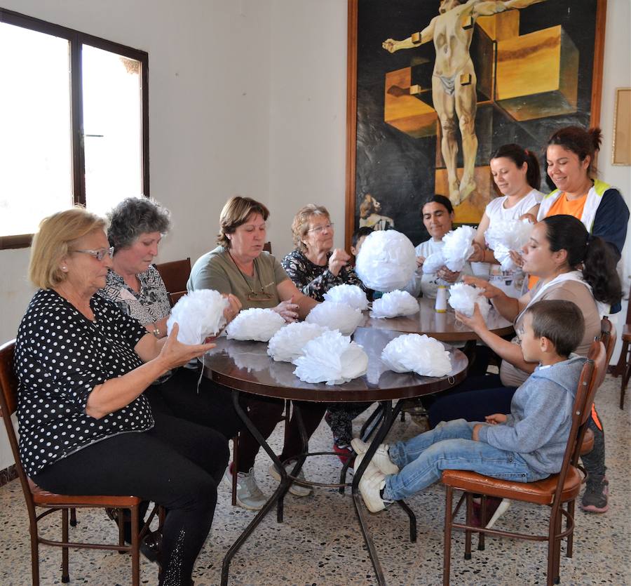 Las vecinas elaboran las flores de papel para adornar. A.P