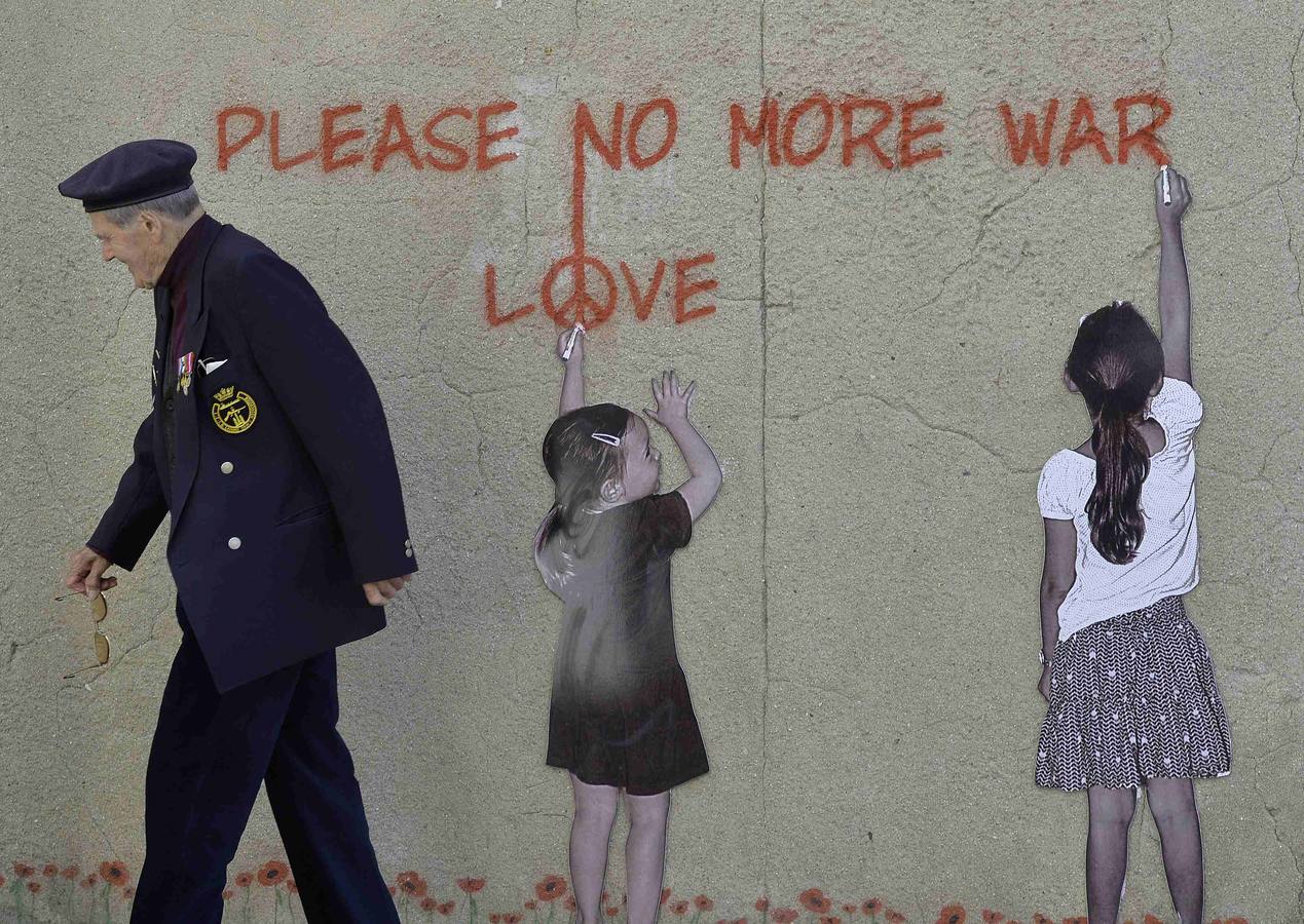 El Veterano británico Paul Butler, de 88 años, pasa frente a un mural en Arromanches-les-Bains, en la costa de Normandía. REUTERS / Toby Melville.