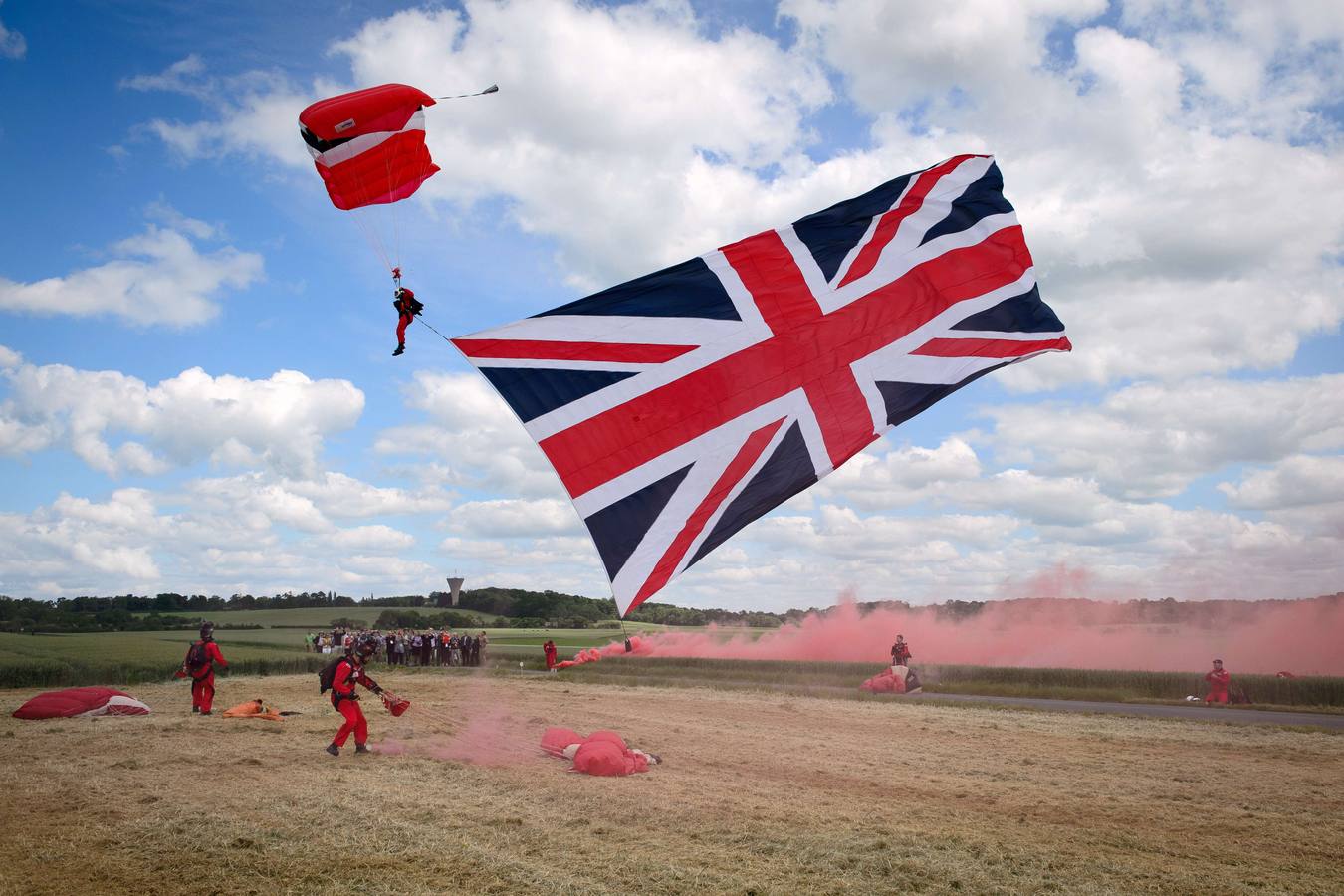 Un soldado suejta una bandera grande de la Unión tras su salto en paracaídas en Ranville, el norte de Francia. AFP PHOTO / POOL / LEON NEAL