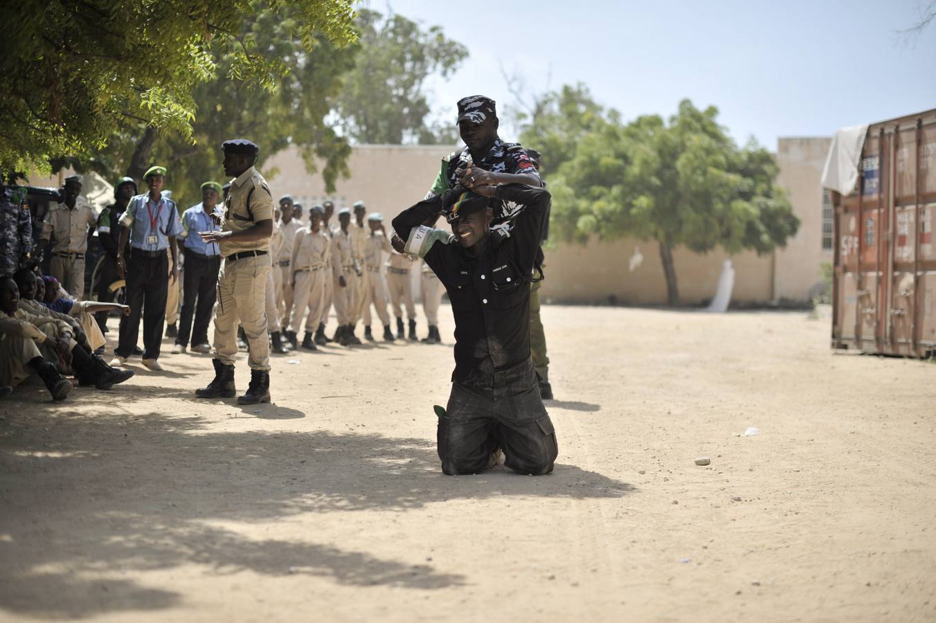 Fotografía que muestra a varios oficiales de policía de la Unión Africana durante un ejercicio de entrenamiento sobre los métodos adecuados para esposar y arrestar a una persona en la academia de policía General Kahiye, en Mogadiscio, Somalia.
