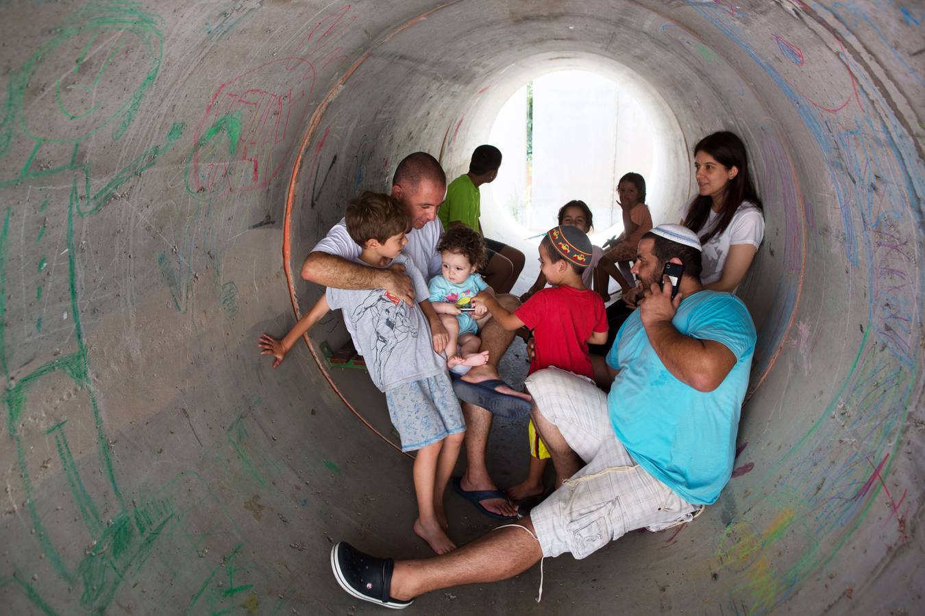 Jueves, 10 de julio. Los israelíes se esconden en un gran tubo de hormigón utilizado como refugio durante un ataque palestino con cohetes en el sur de la aldea israelí de Nitzan. AFP FOTO / MENAHEM KAHANA