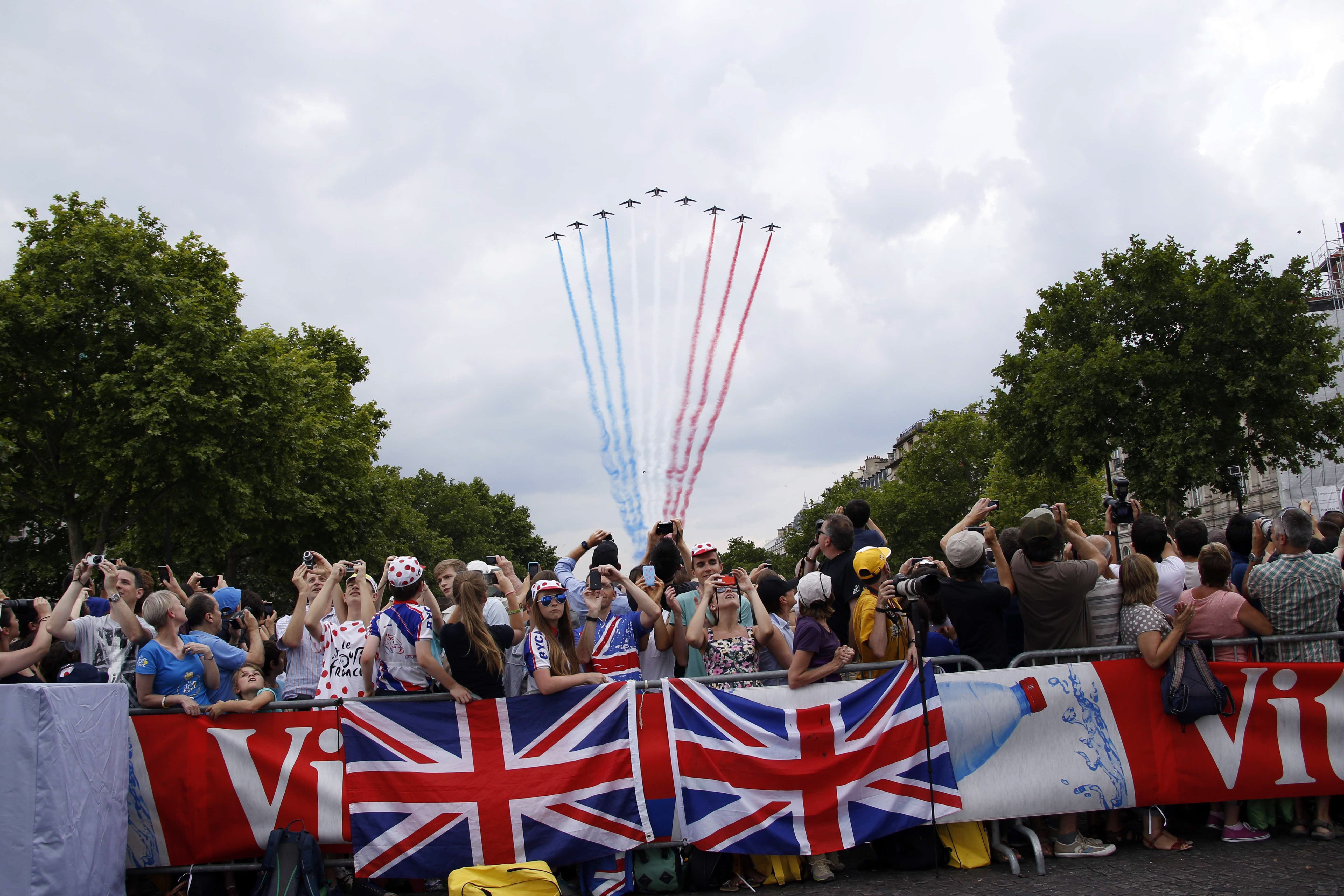 Aficionados, a la espera de la llegada de los corredores con aviones dibujando la bandera francesa en el cielo.