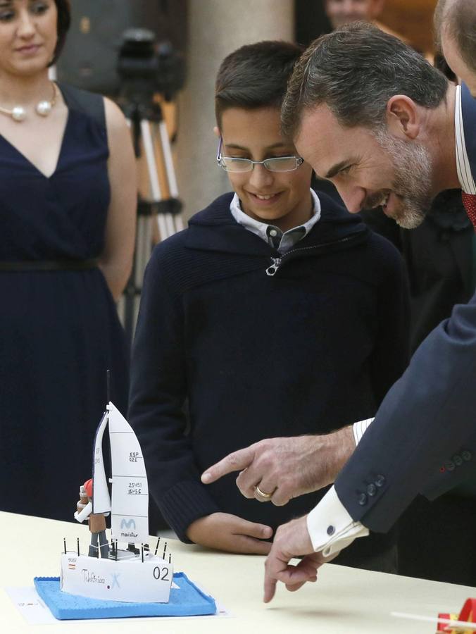 El rey Felipe VI observa el trabajo de una de las niños ganadoras de la XXXII y XXXIII ediciones del concurso escolar '¿Qué es un Rey para ti?'.