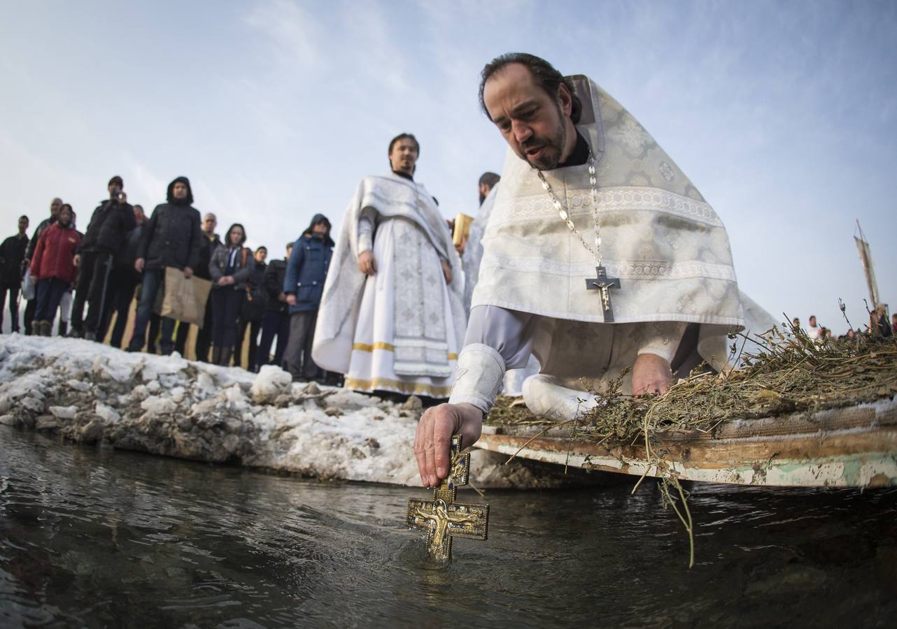 Un sacerdote ortodoxo sumerge una cruz en el río Bolshaya Almatinka para bendecir el agua durante la ceremonia de la Epifanía, en Almaty. Los creyentes ortodoxos que respetan el calendario juliano marca de la Epifanía el 19 de enero y se sumergen en aguas heladas sin importarles la temperatura. Fotografía: REUTERS-Shamil Zhumatov.