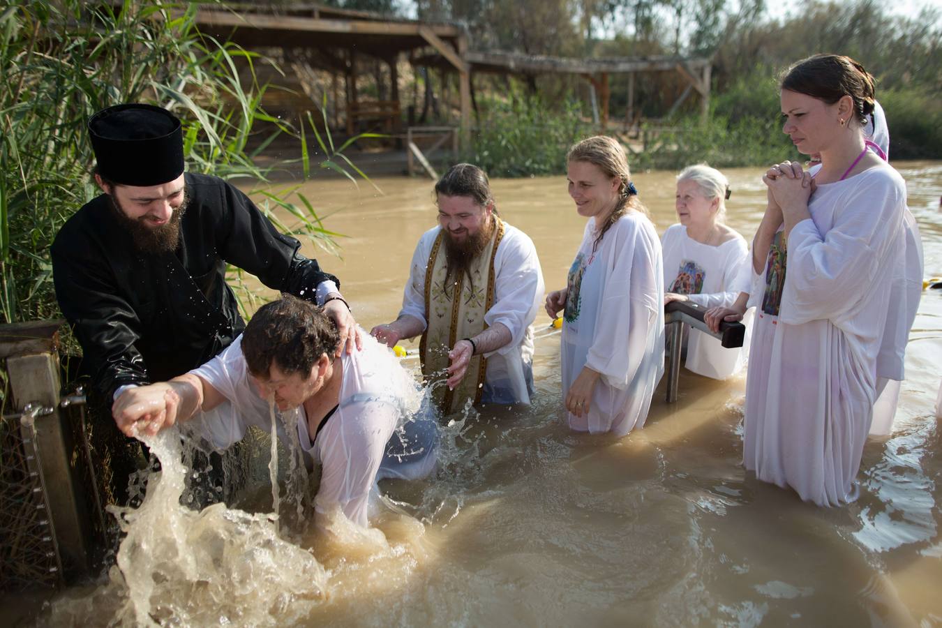 Sacerdotes ortodoxos cristianos bautizan a un peregrino en las aguas del río Jordán durante una ceremonia de bautismo como parte de la fiesta ortodoxa de la Epifanía. Fotografía: AFP-Menahem Kahan