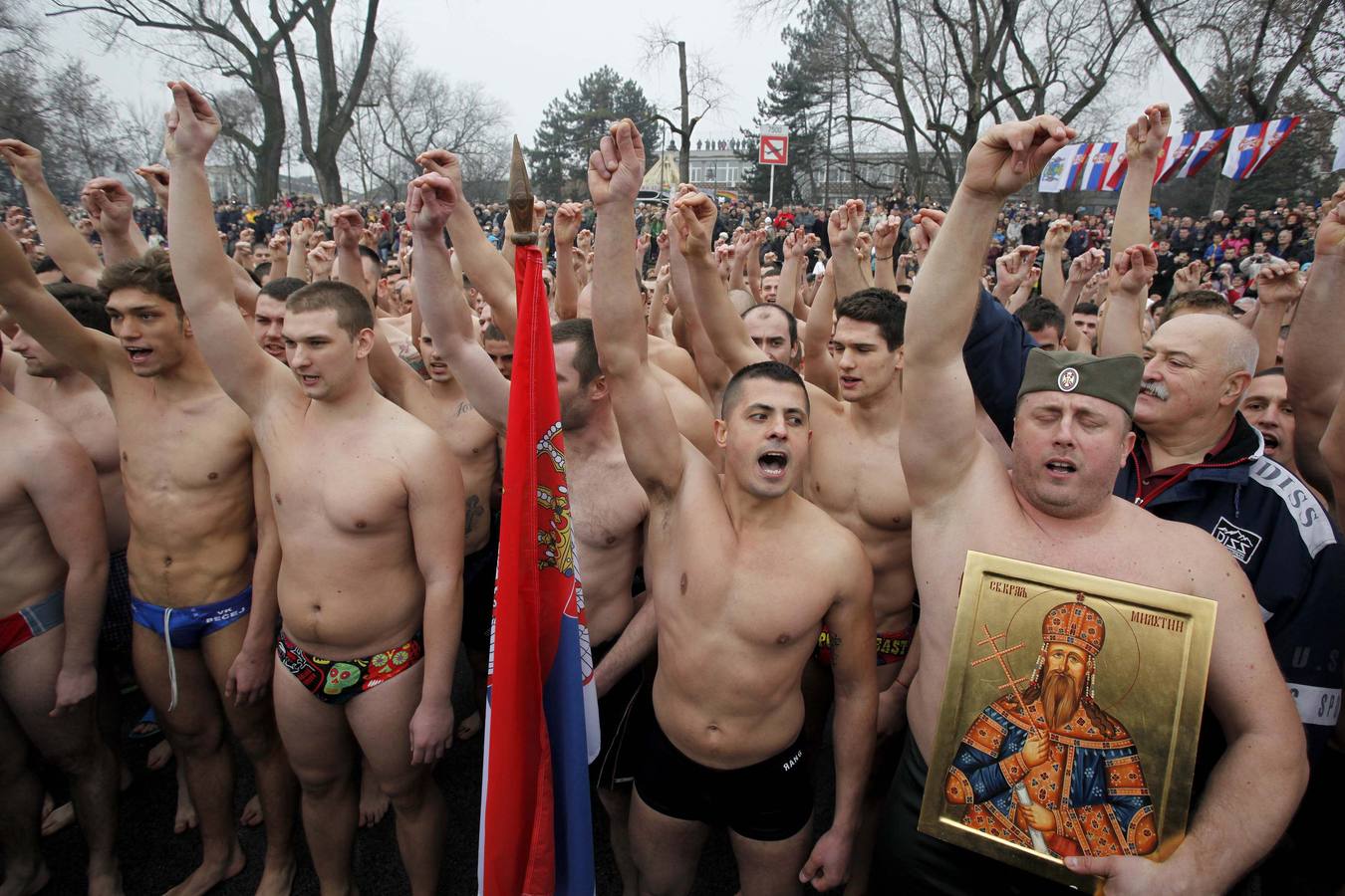 Hombres rezando y realizando el saludo tradicional serbio con tres dedos, antes de lanzarse al agua para tratar de coger la cruz de madera durante la celebración de la festividad de la Epifanía en Belgrado, Serbia. Fotografía: Reuters-Djordje Kojadinovic