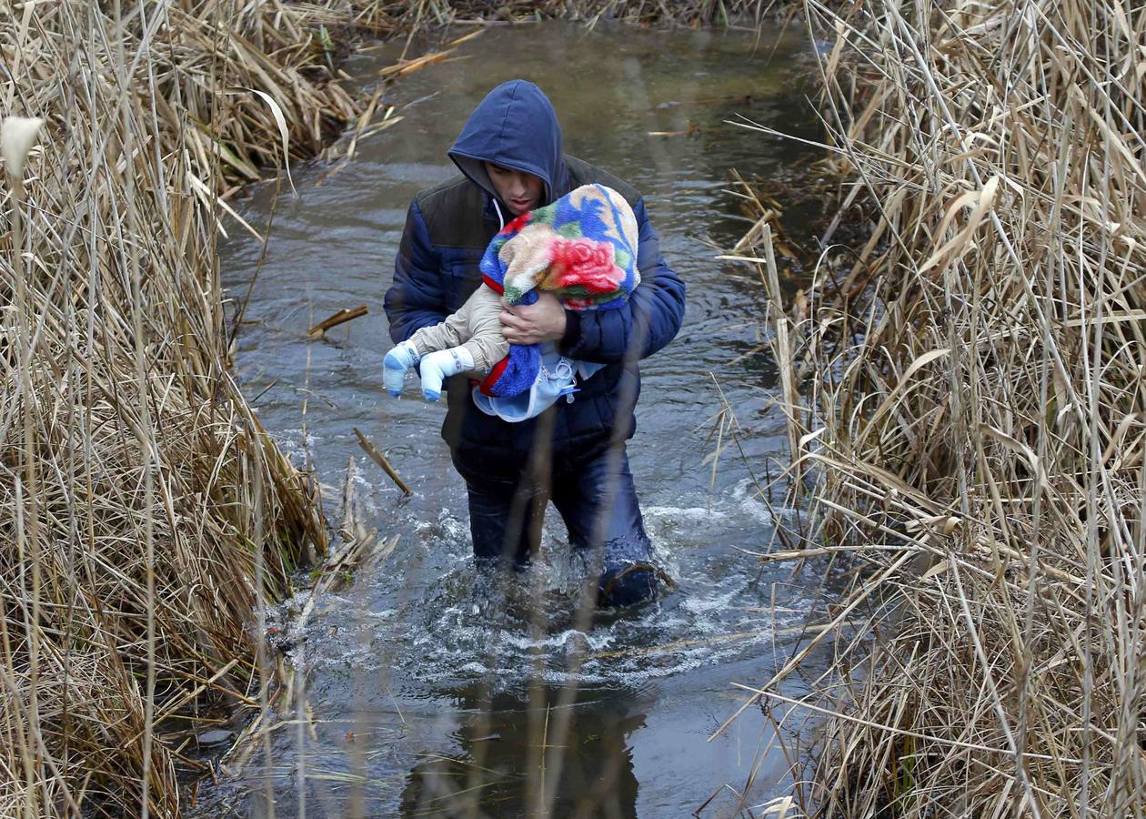 Un hombre de Kosovo lleva a su bebé mientras cruza ilegalmente la frontera entre Hungría y Serbia, cerca del pueblo de Ásotthalom. Fotografía: REUTERS / Lazlo Balogh.