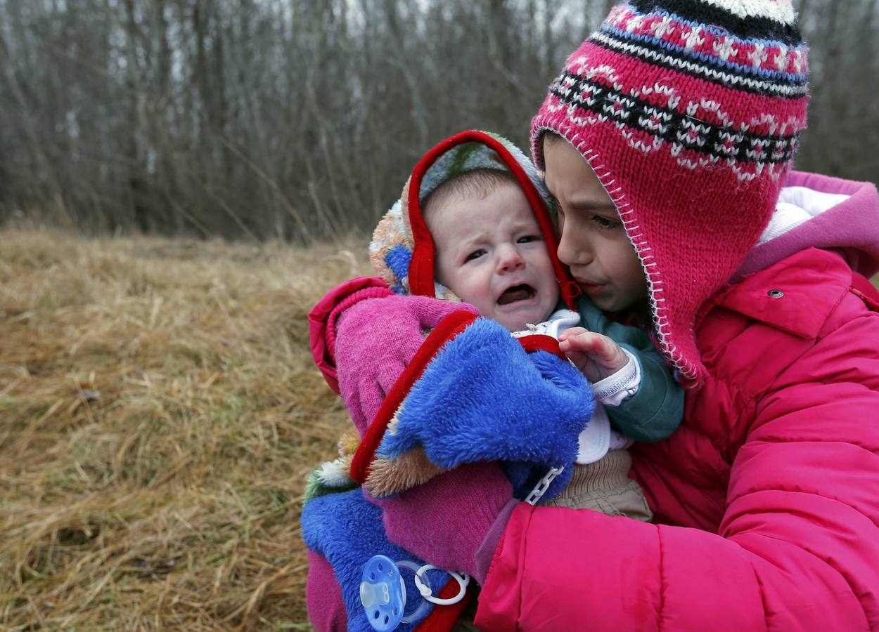 Un hombre de Kosovo lleva a su bebé mientras cruza ilegalmente la frontera entre Hungría y Serbia, cerca del pueblo de Ásotthalom. Fotografía: REUTERS / Lazlo Balogh.