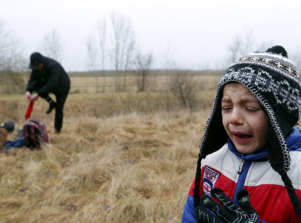 Un hombre de Kosovo lleva a su bebé mientras cruza ilegalmente la frontera entre Hungría y Serbia, cerca del pueblo de Ásotthalom. Fotografía: REUTERS / Lazlo Balogh.