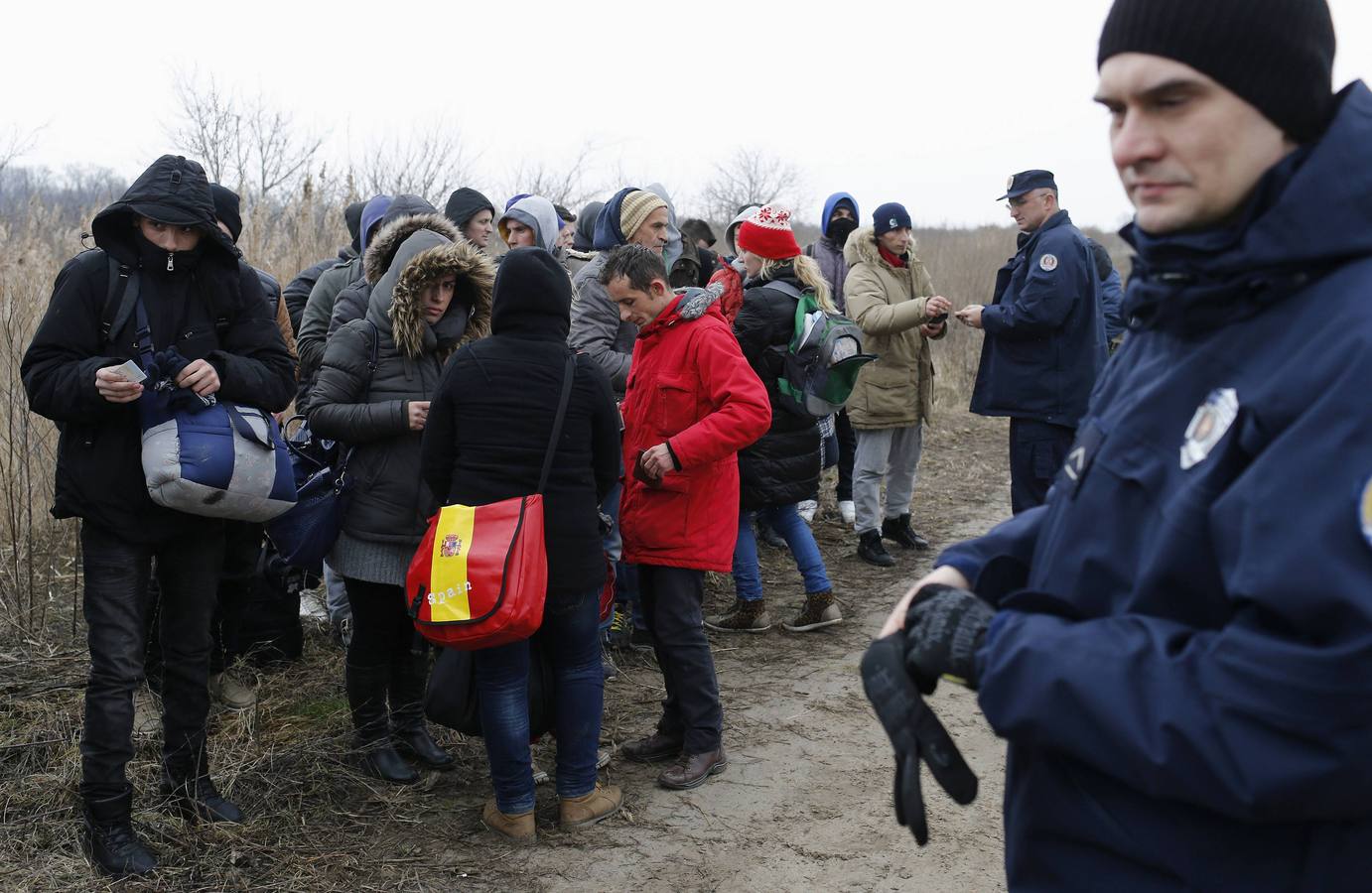 Un policía serbio recoge la documentación de un grupo de habitantes de Kosovo, después de que fueran detenidos cuando trataban de cruzar la frontera hacia Hungría, cerca de la ciudad de Subotica. Fotografía: REUTERS / Marko Djurica