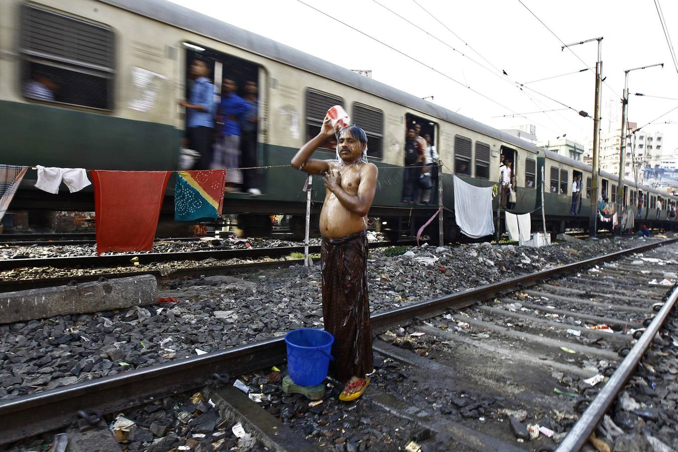 Un hombre se da un baño en la estación de tren cerca de Calcuta