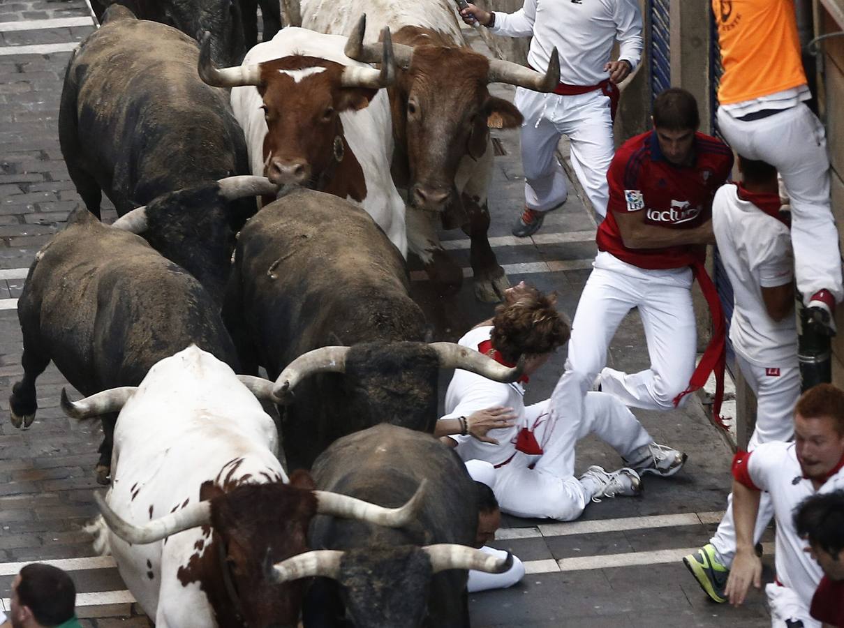 Algunos mozos caen bajo los toros a su paso.