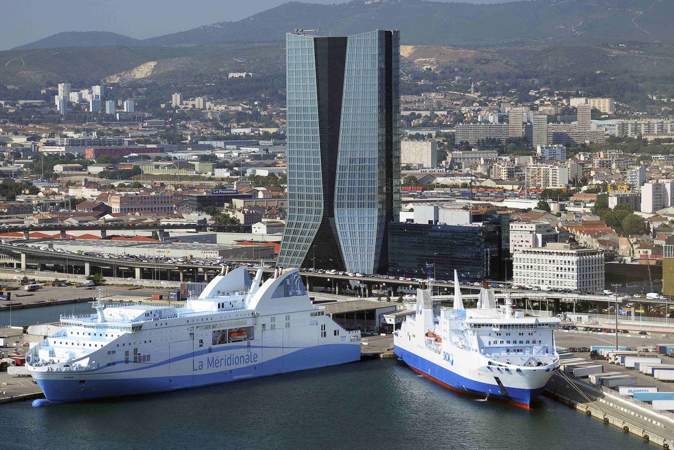 Una vista aérea del ferry "Piana" operado por la empresa CMN La Meridionale (L) y el ferry "Paglia Orba" operado por la SNCM (Sociedad Nacional Marítima Córcega-Mediterráneo) amarrado en frente de la sede de la CMA-CGM shipping Company en Marsella
