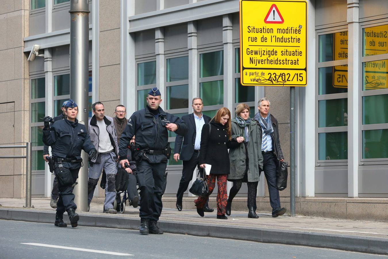 Agentes escoltan a varias personas fuera del perímetro de seguridad establecido alrededor de la estación de metro de Maalbeek.